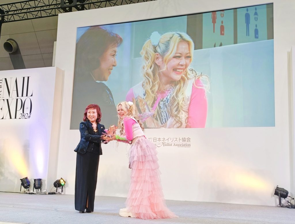 金子実由喜副理事長からトロフィーを受け取るエルフ荒川さん